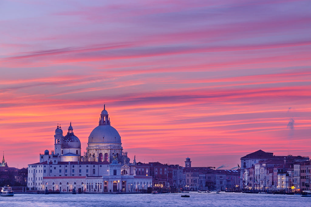 Cityscape with a prominent building under a vibrant pink and purple sunset sky.